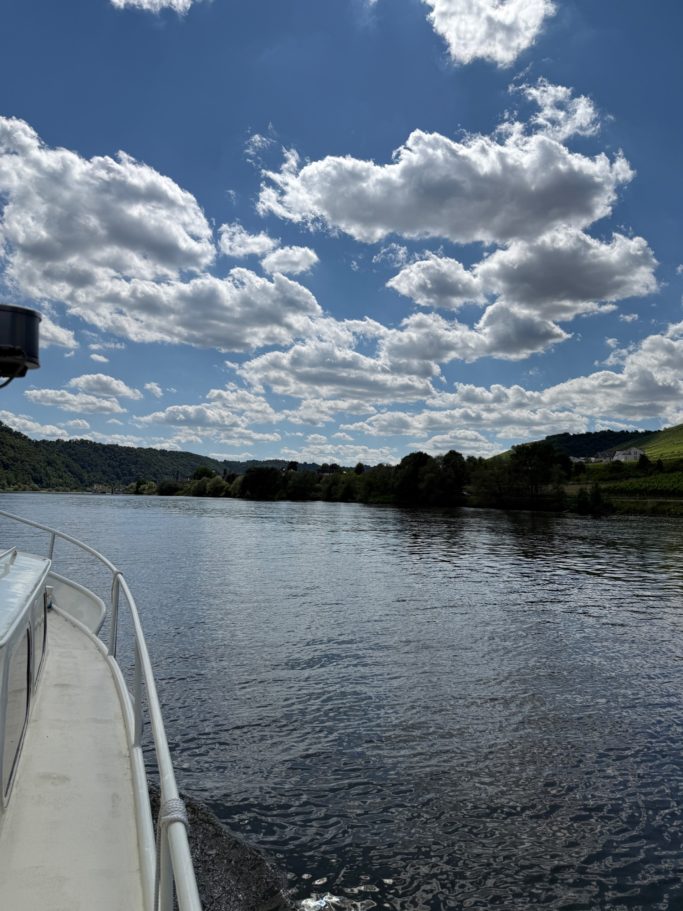 Blick auf einen Fluss mit sanften Wellen, umgeben von Hügeln und Wolkenhimmel.